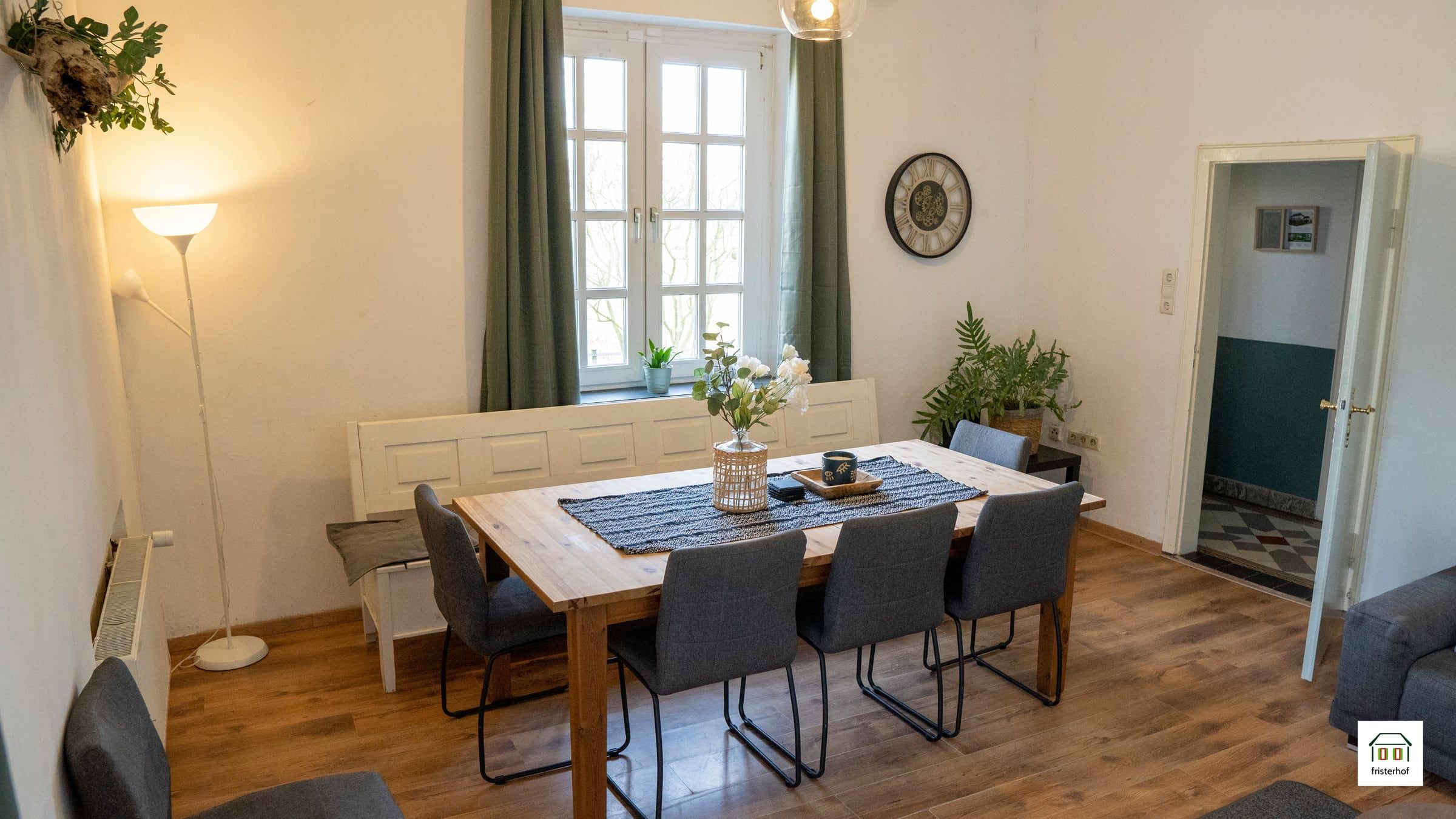 Grote eettafel in de woonkamer voor een raam met groene gordijnen